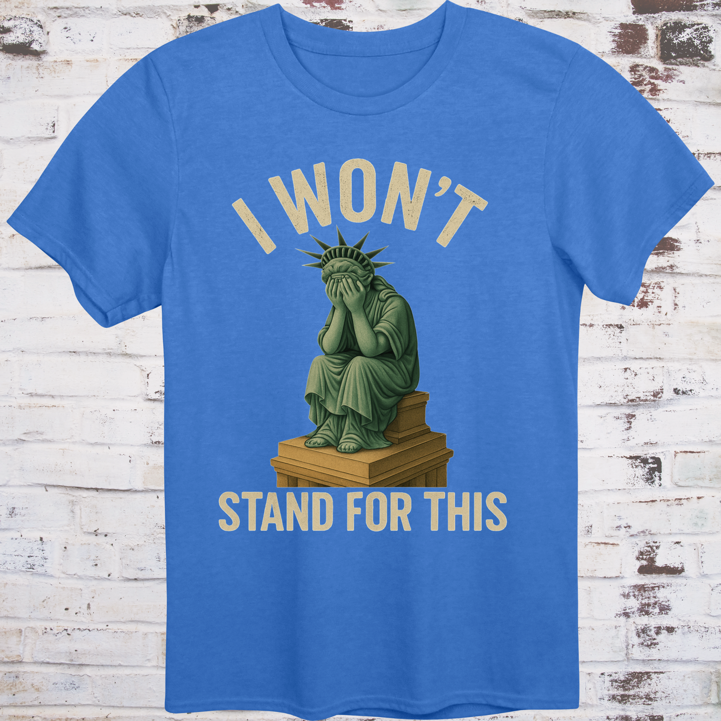 Blue t-shirt with illustration of the Statue of Liberty  
sitting on a pedestal with her face in her hands,  
under text reading "I Won’t Stand for This" –  
progressive protest shirt by Democratee’s