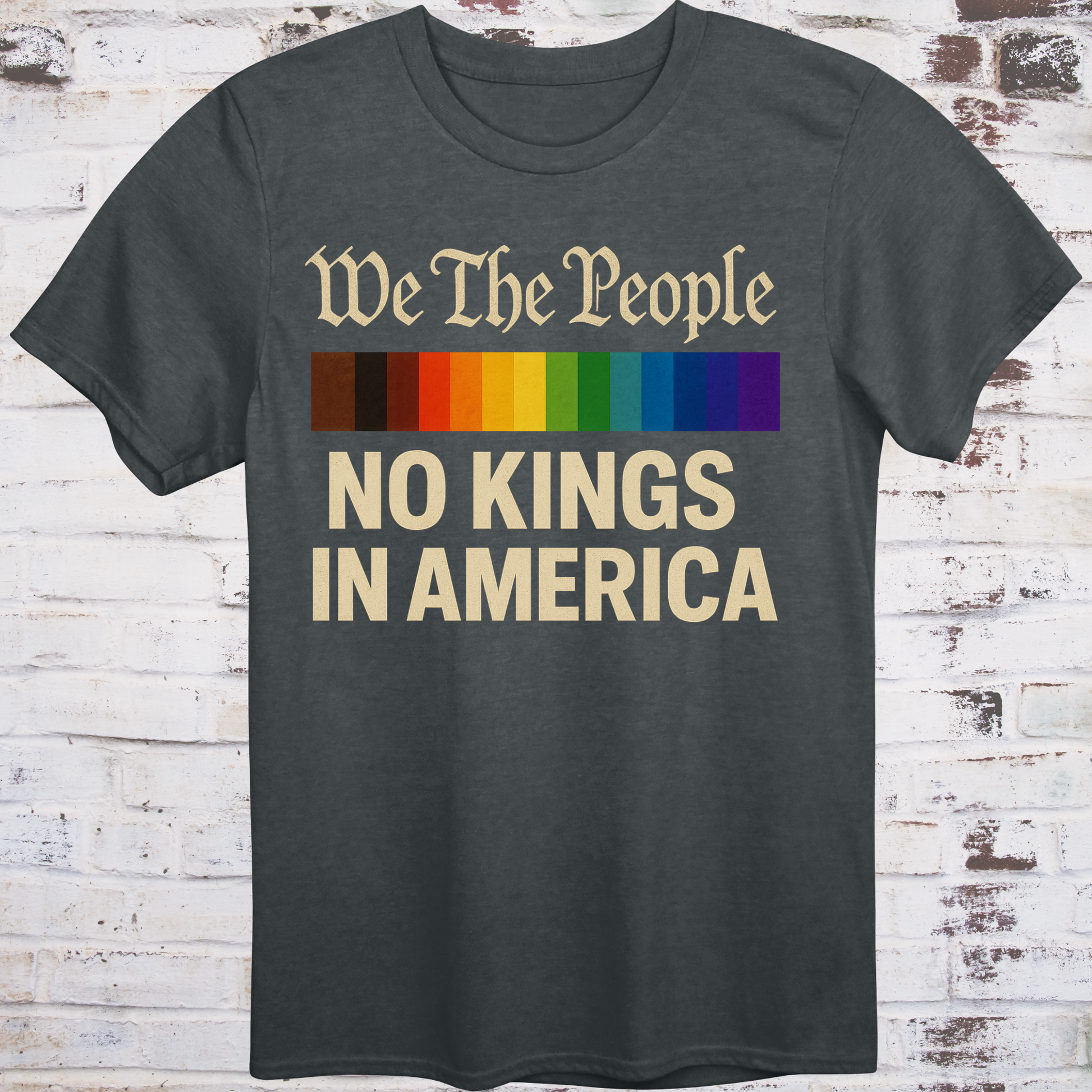 Gray t-shirt with the phrase 'We The People' in old script above a Progress Pride flag, and bold text below reading 'No Kings in America' — a pro-democracy, LGBTQ+ inclusive design."