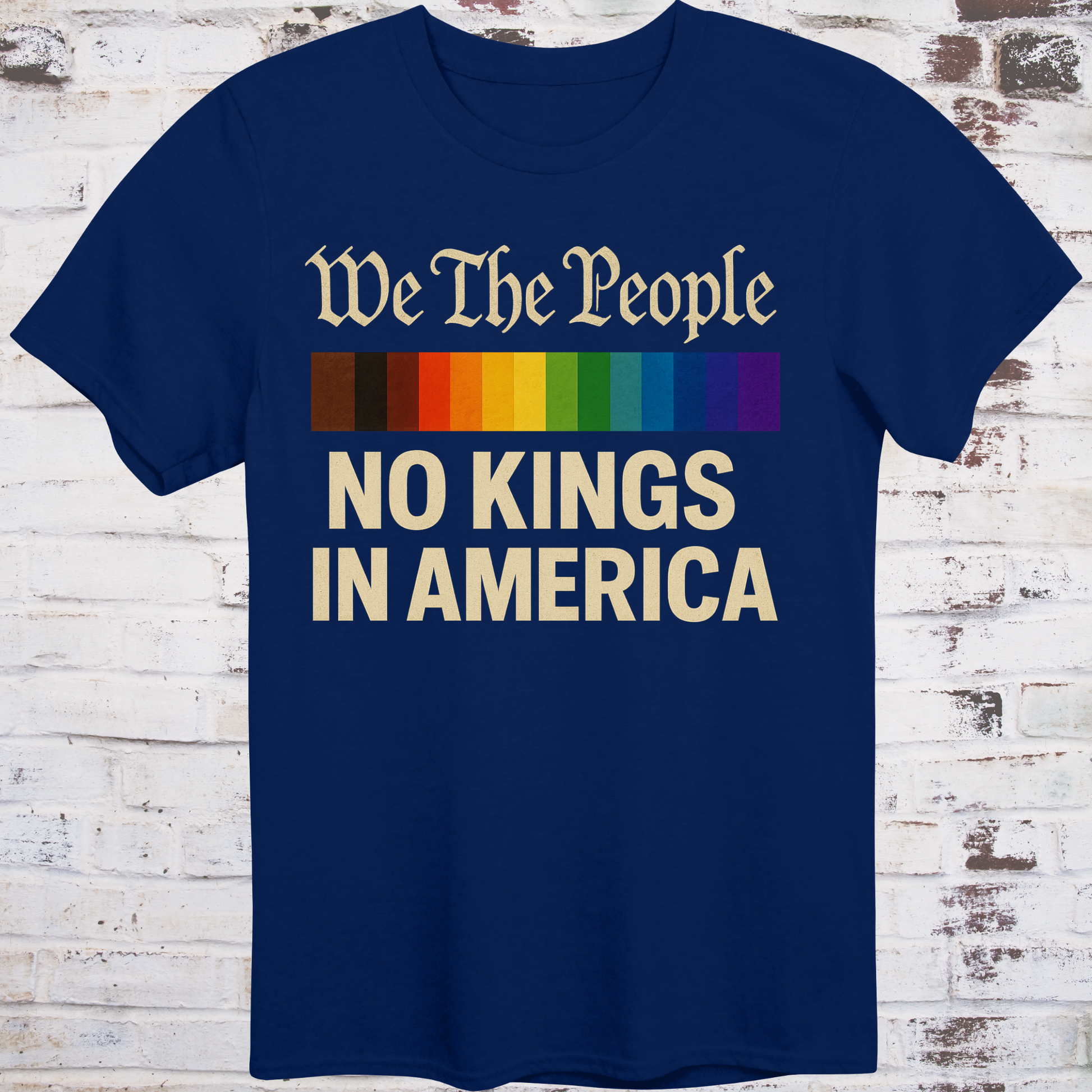 Navy t-shirt with the phrase 'We The People' in old script above a Progress Pride flag, and bold text below reading 'No Kings in America' — a pro-democracy, LGBTQ+ inclusive design."