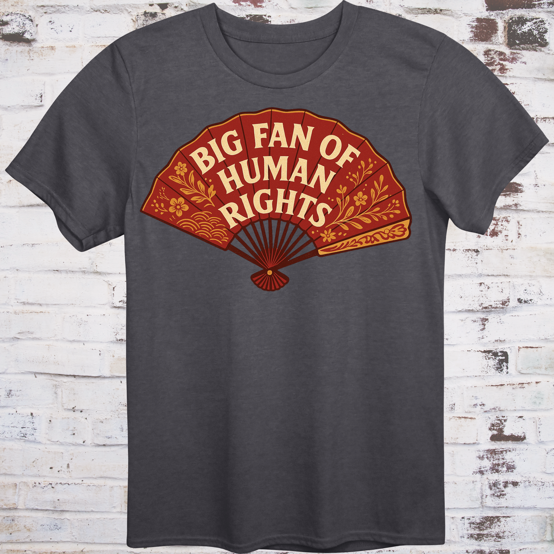 Gray t-shirt with a red and orange graphic of a fan and text 'Big Fan of Human Rights' on a wooden background.