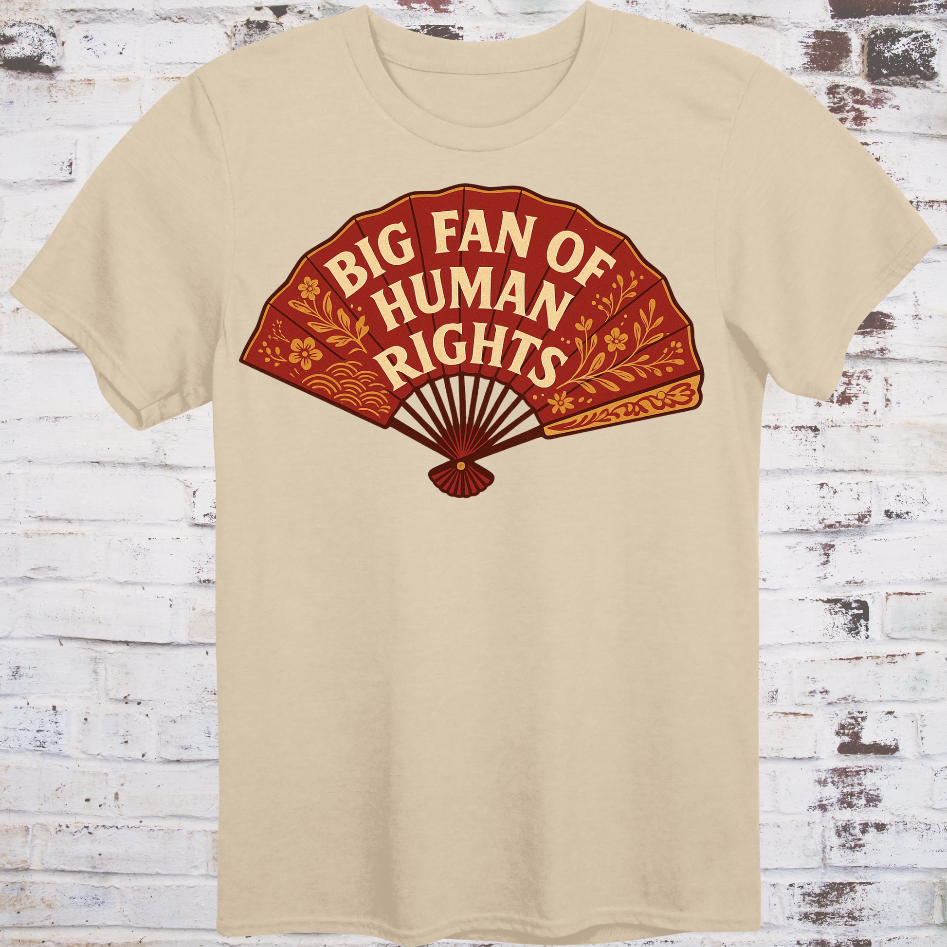 Beige t-shirt with a red graphic of a fan and text 'Big Fan of Human Rights' on a wooden background