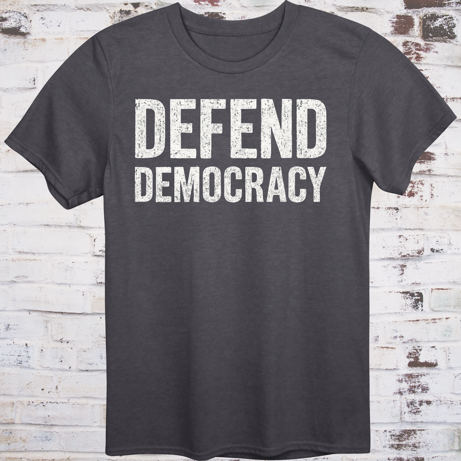 Dark gray t-shirt with 'DEFEND DEMOCRACY' text on a wooden background