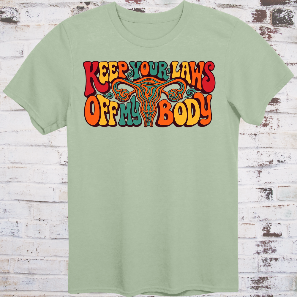 Keep Your Laws Off My Body in massive interlocking 70s bubble letters in deep red, teal, and orange around a stylized uterus, on a warm mustard yellow background.