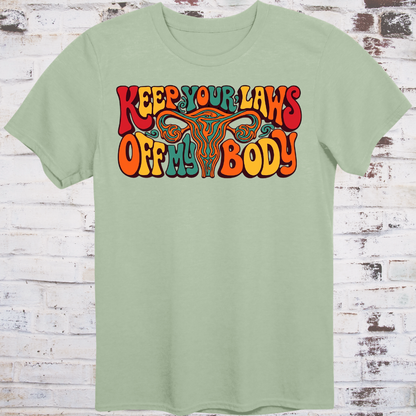 Keep Your Laws Off My Body in massive interlocking 70s bubble letters in deep red, teal, and orange around a stylized uterus, on a warm mustard yellow background.