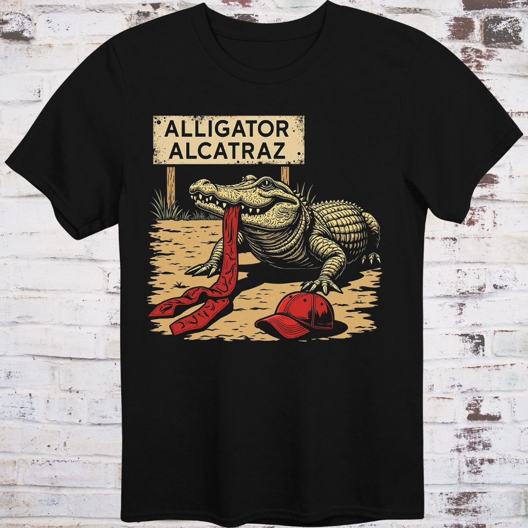 Black t-shirt with an alligator graphic and 'Alligator Alcatraz' sign on a wooden background