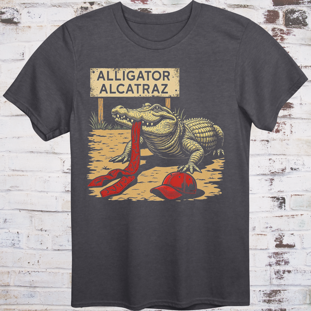 Black t-shirt with an alligator graphic and 'Alligator Alcatraz' text on a wooden background